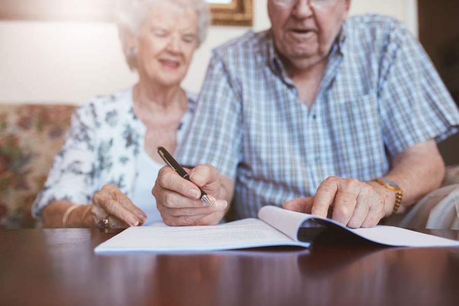 elderly man signing papers for an estate planning lawyers McAllen agency